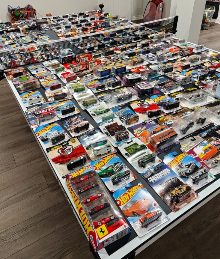 Hundreds of carded die-cast cars laid out edge to edge across a large table